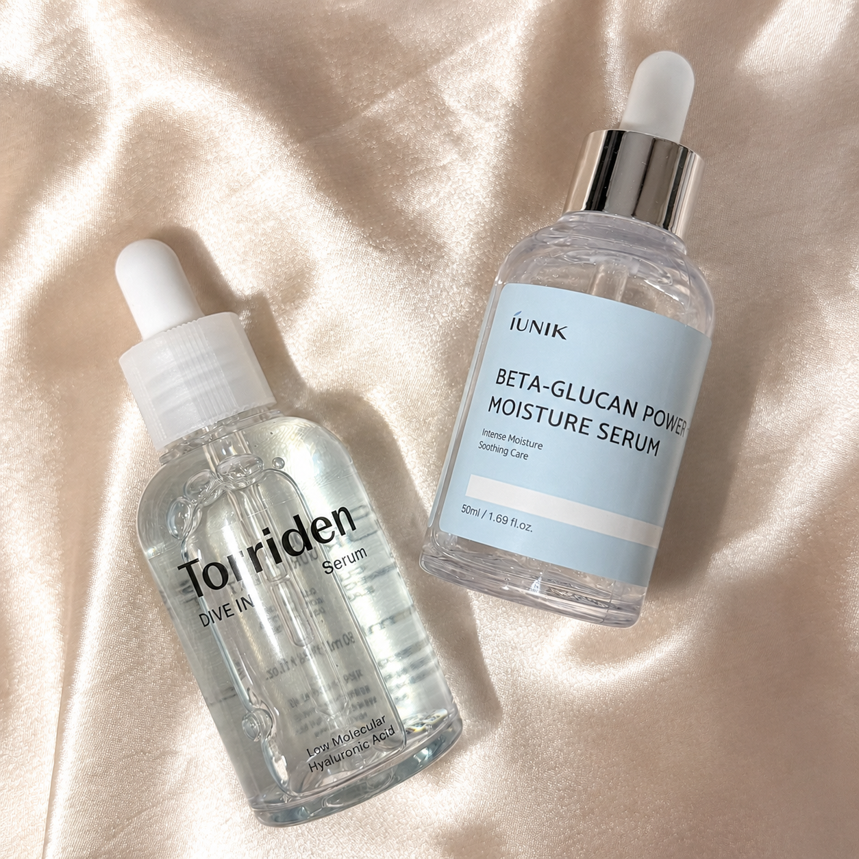 Torriden Dive In Serum next to iUNIK Beta-Glucan Power Moisture Serum on satin fabric